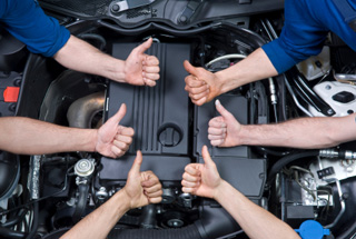 Mechanics giving an inspected car a thumbs up